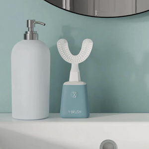 Y-Brush dental device on a bathroom counter with a soap dispenser.